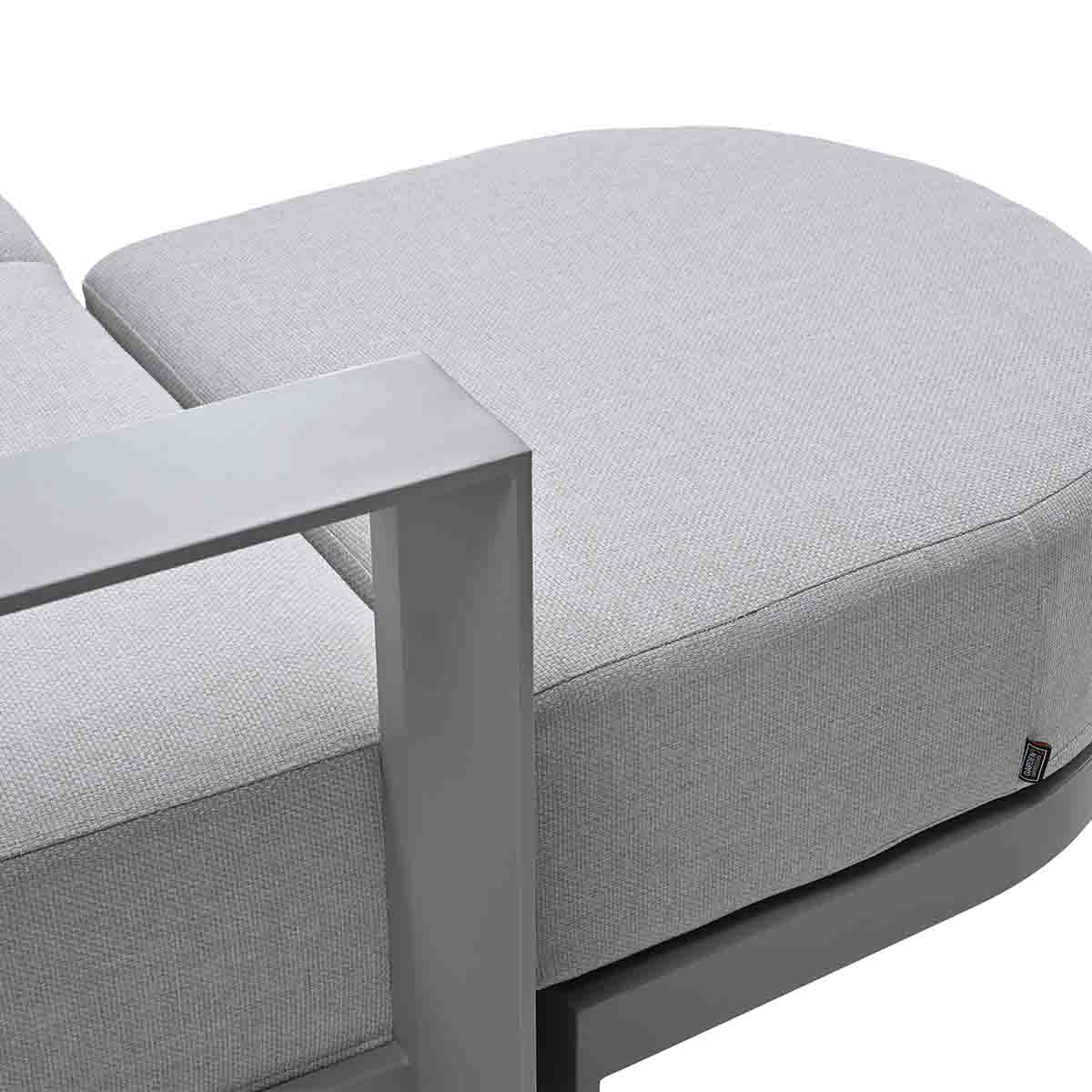 Een grijze moderne fauteuil met gestoffeerde zitting en armleuning.