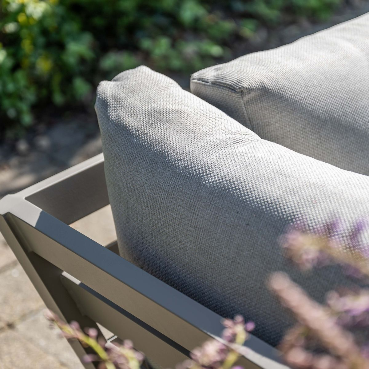 Gray cushions on outdoor furniture, with greenery in the background.