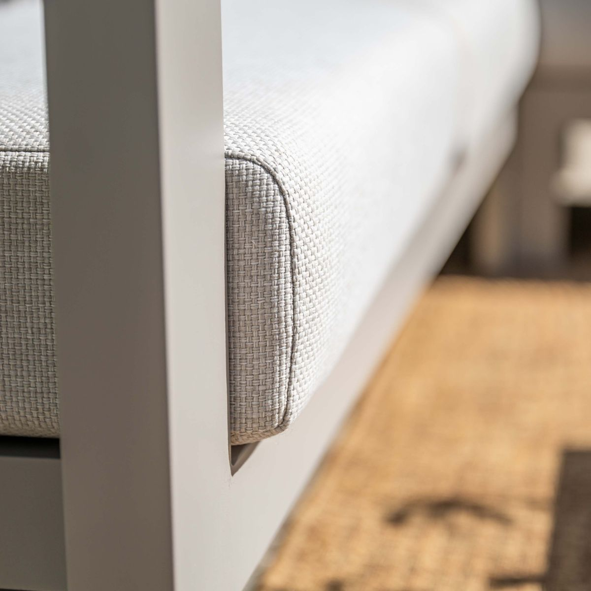 Gray sofa with textured upholstery and white frame on a rug.