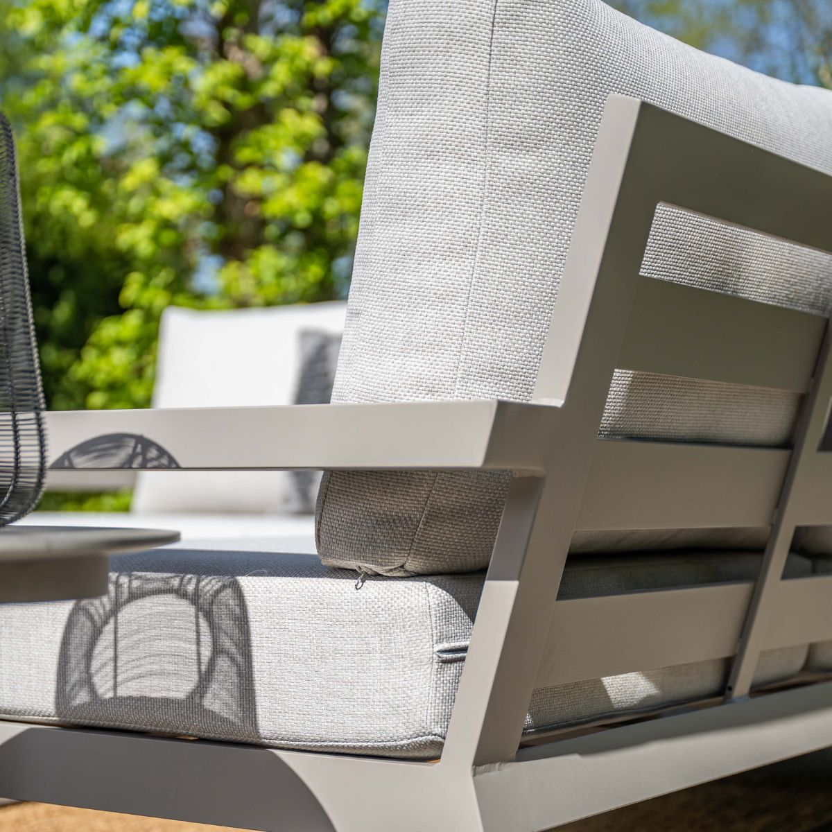 Gray outdoor sofa with cushions, trees visible in the background.