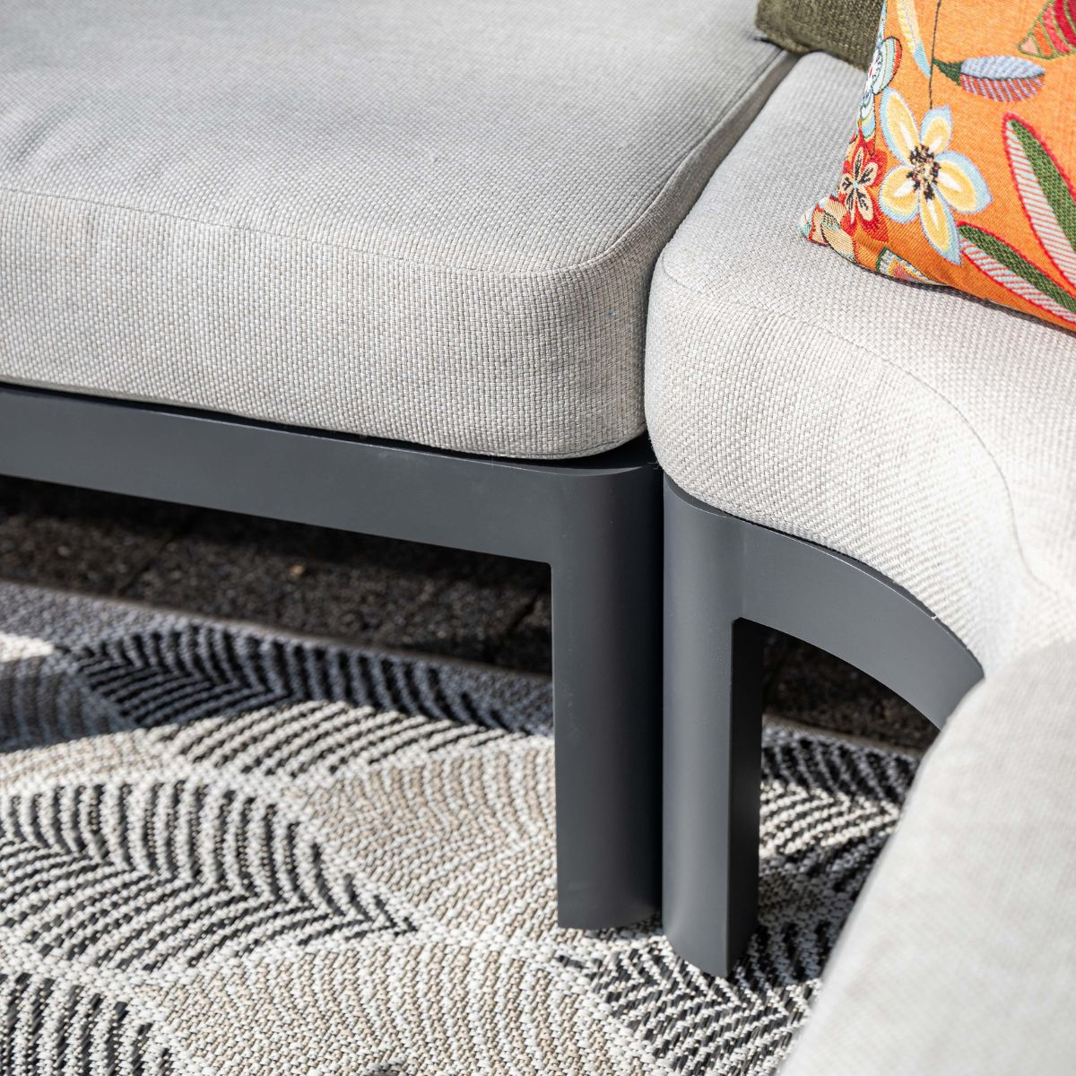 Gray outdoor furniture on a patterned rug with colorful cushions.