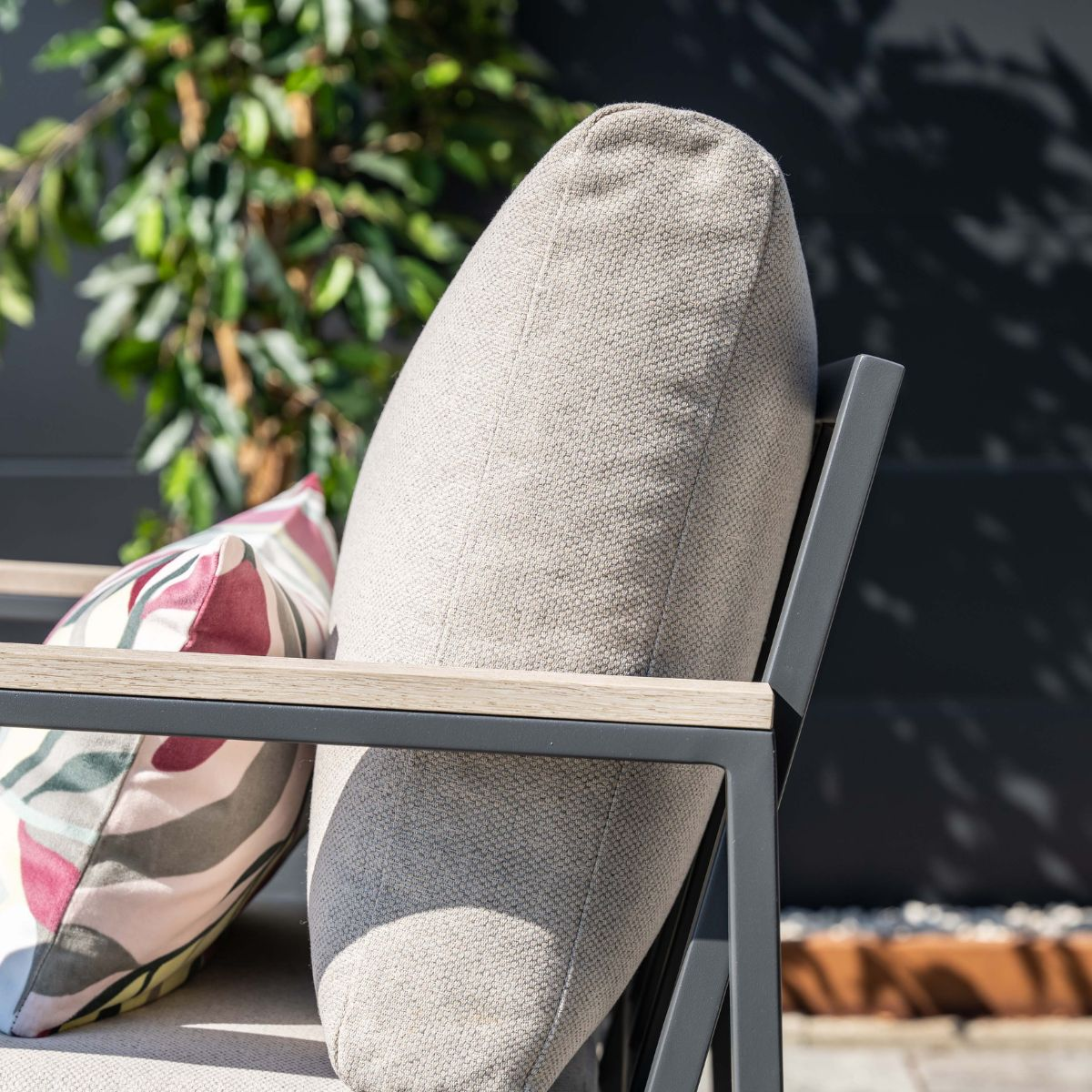 A grey cushion and a patterned cushion on an outdoor chair.