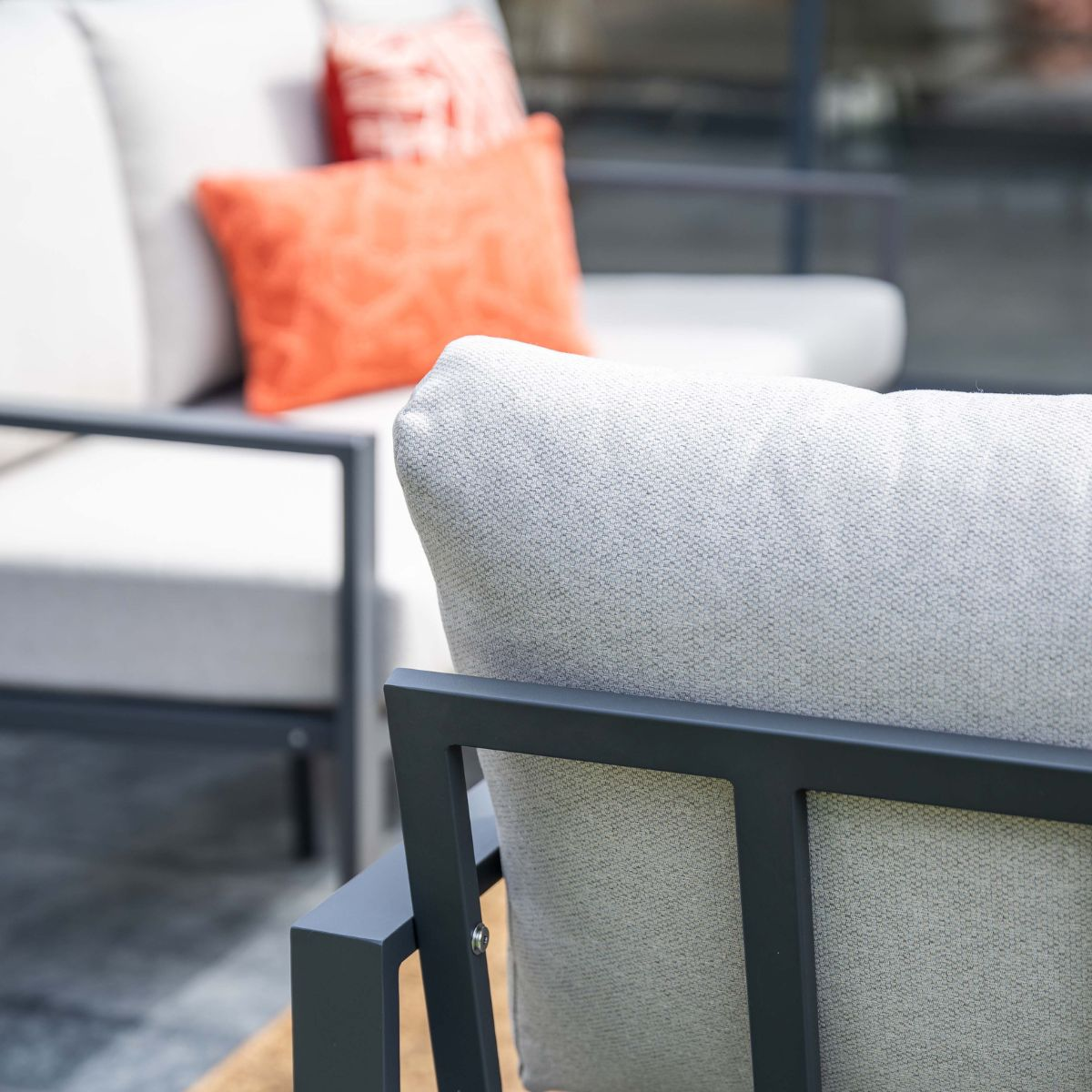 Outdoor furniture with light gray cushions and orange accent pillows.