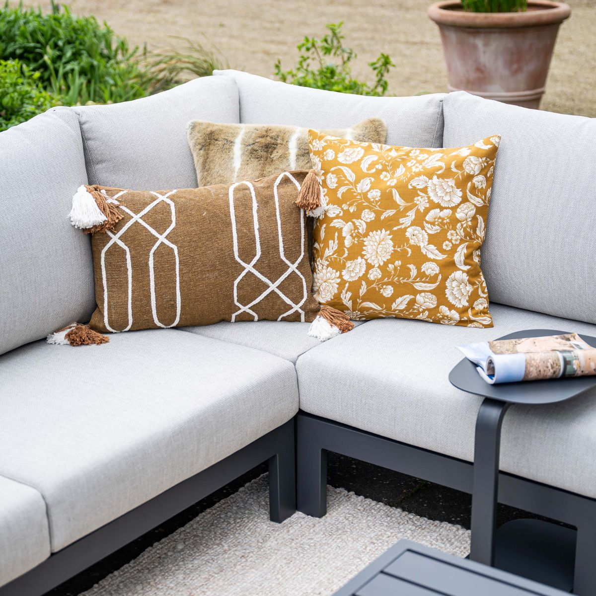 Gray sectional sofa with pillows, one floral, one geometric pattern.
