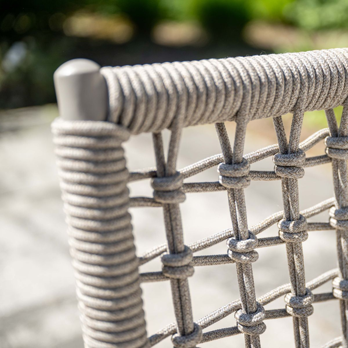 Gray rope chair with visible weaving and knots outdoors.