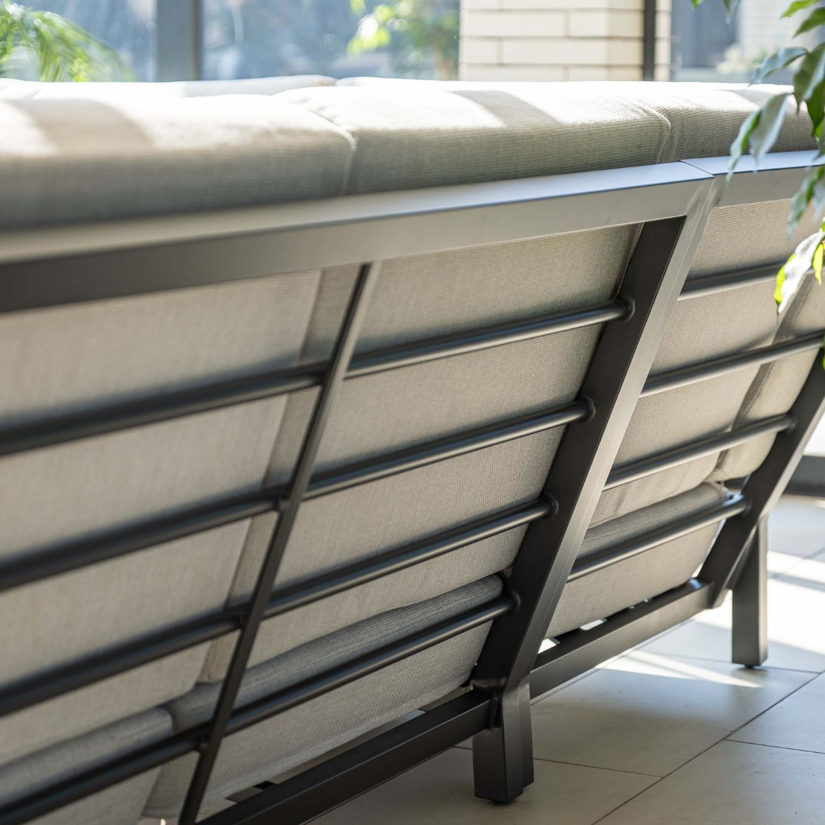 Gray outdoor sofa with metal frame, visible back details, sunny.