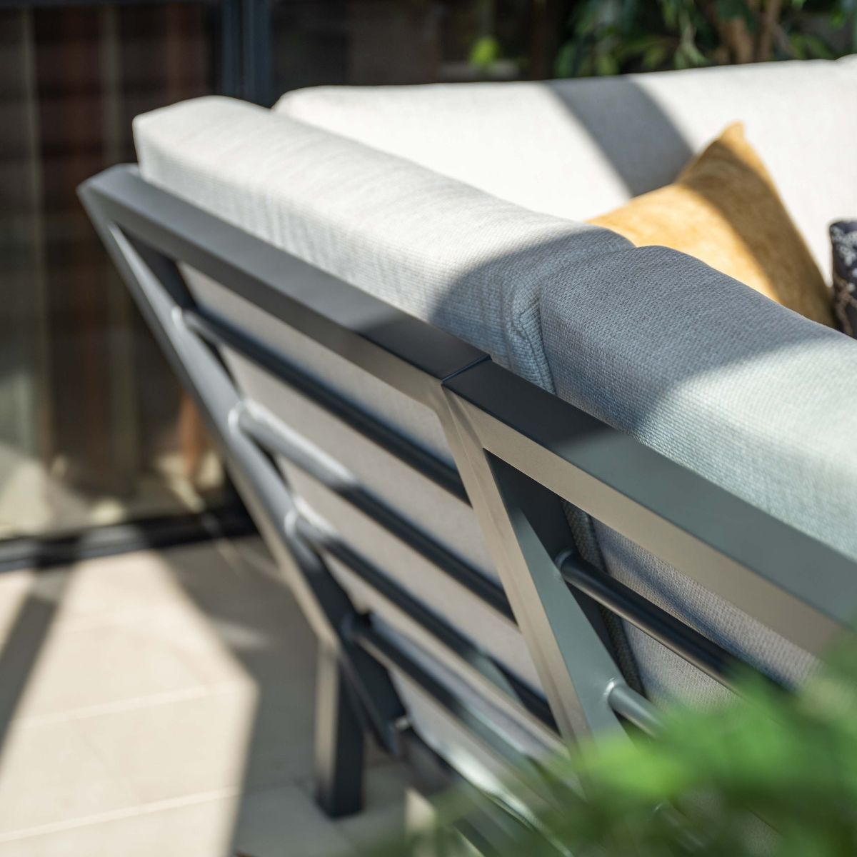 Gray outdoor sofa with metal frame and yellow accent pillow.