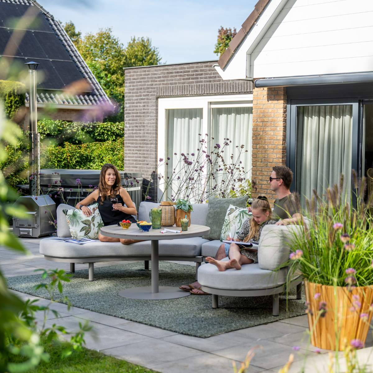 Family relaxes on outdoor patio furniture. Man, woman, and child enjoy a sunny day.