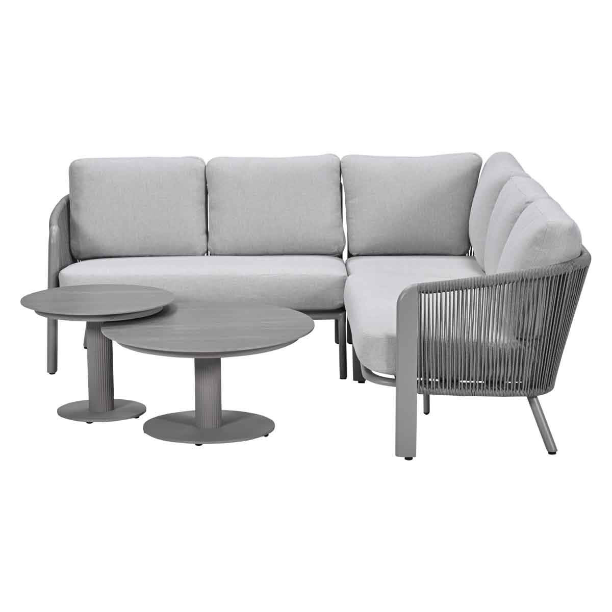 A grey sectional sofa with white cushions and round grey coffee tables.
