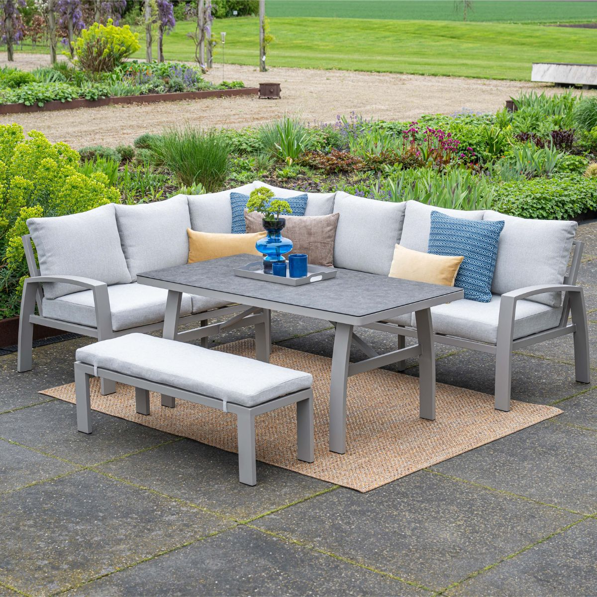 Grijze loungeset voor buiten met tafel en bank op een kleed.