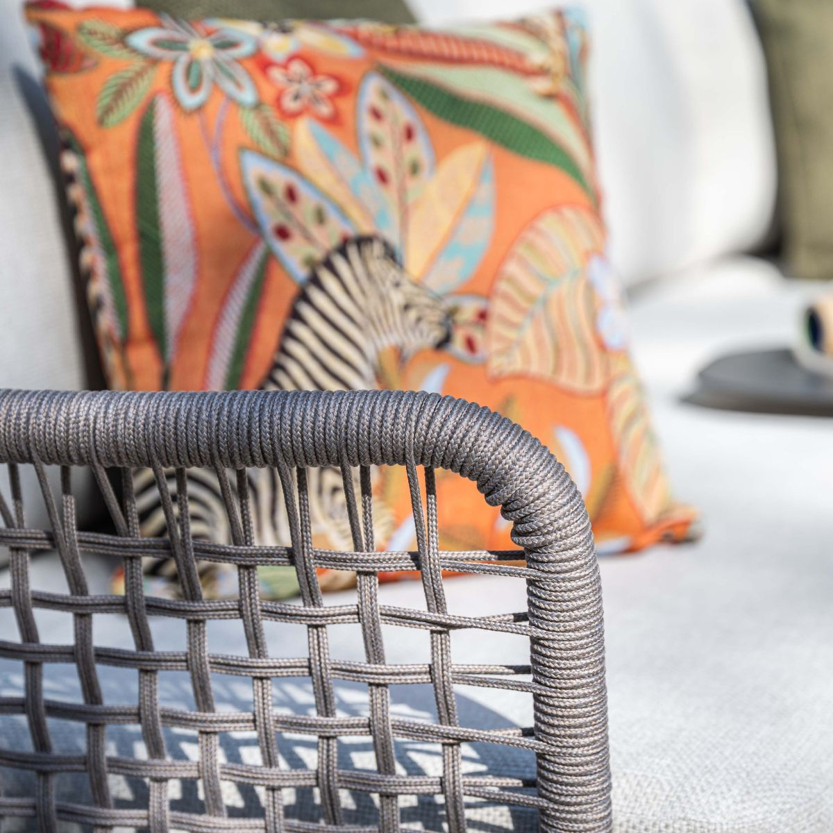 Gray woven armchair with a jungle-zebra print cushion.