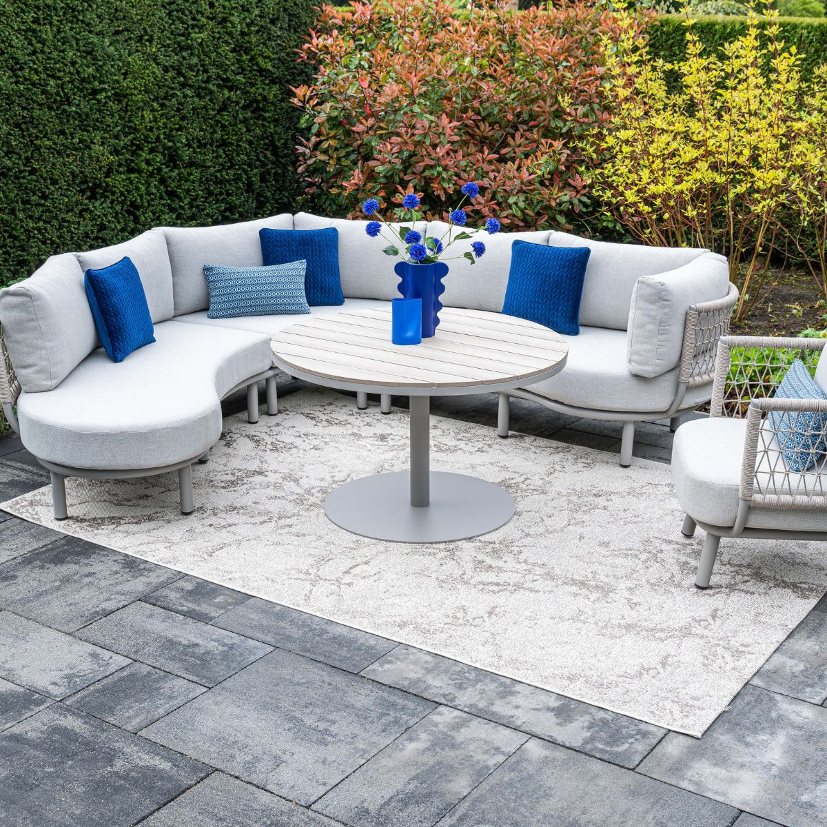 Buitenmeubelset met bank, tafel en fauteuil op een terras.