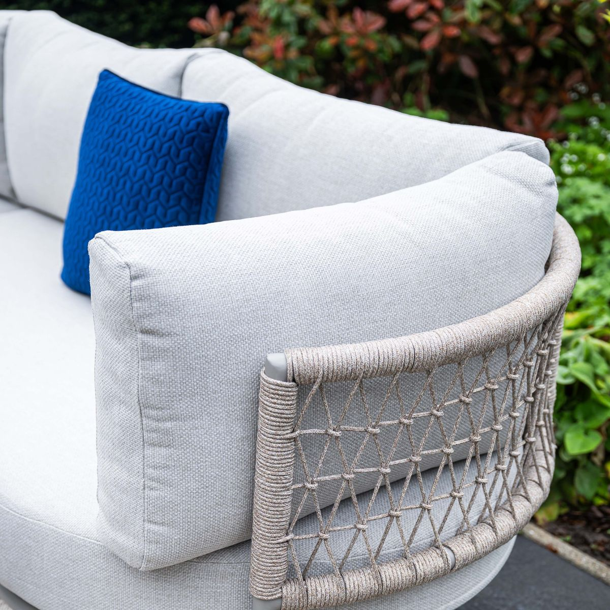 Grijze buitenbank met blauw kussenaccent en touwdetails aan de zijkant.