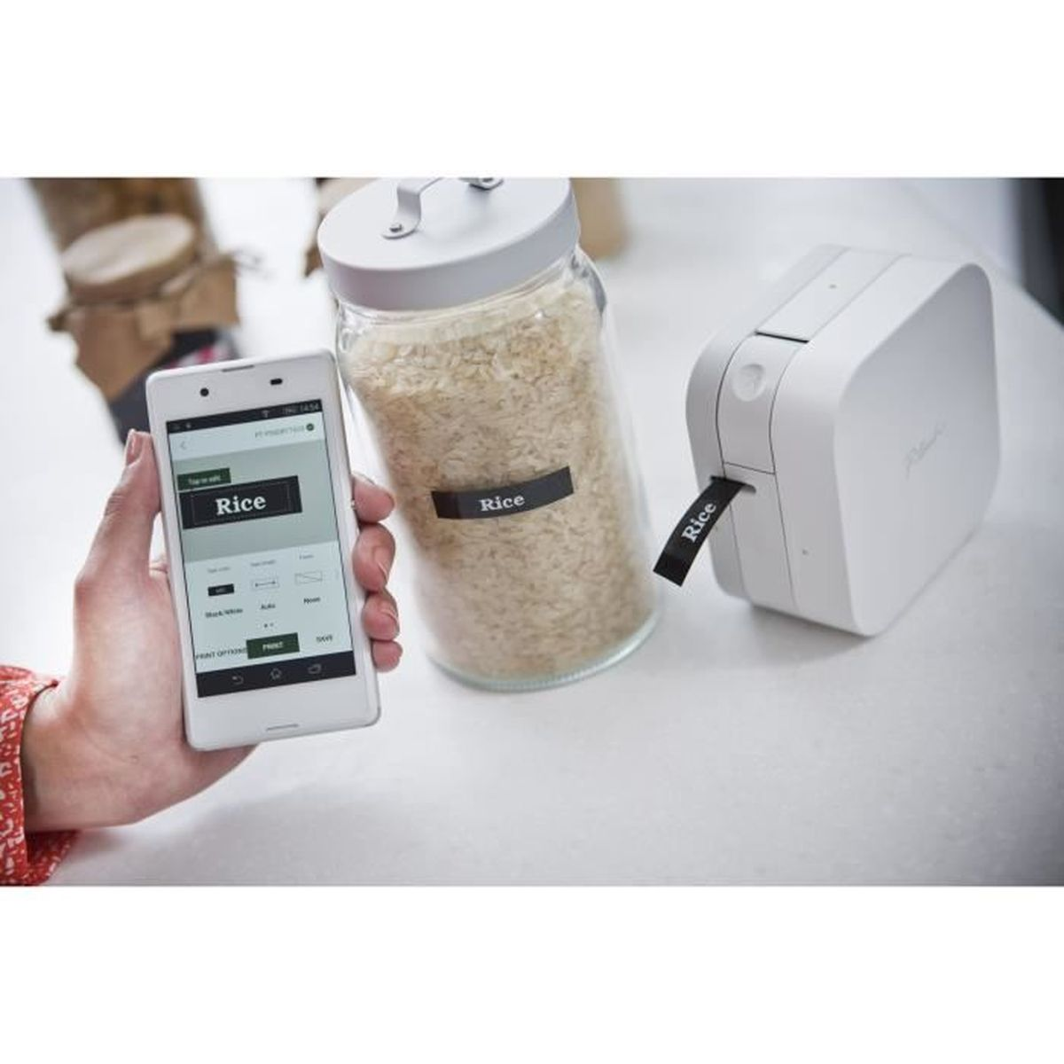 Un smartphone affiche des étiquettes à côté d'un pot de riz et d'une imprimante.
