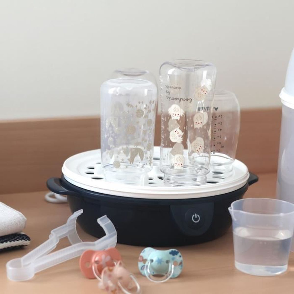 Ein Dampfsterilisator mit Babyflaschen, Schnullern und Zange.