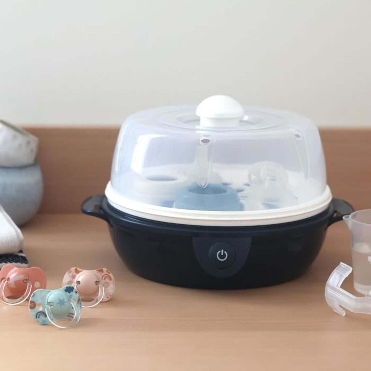Ein Dampfsterilisator für Babyflaschen mit Schnullern davor.