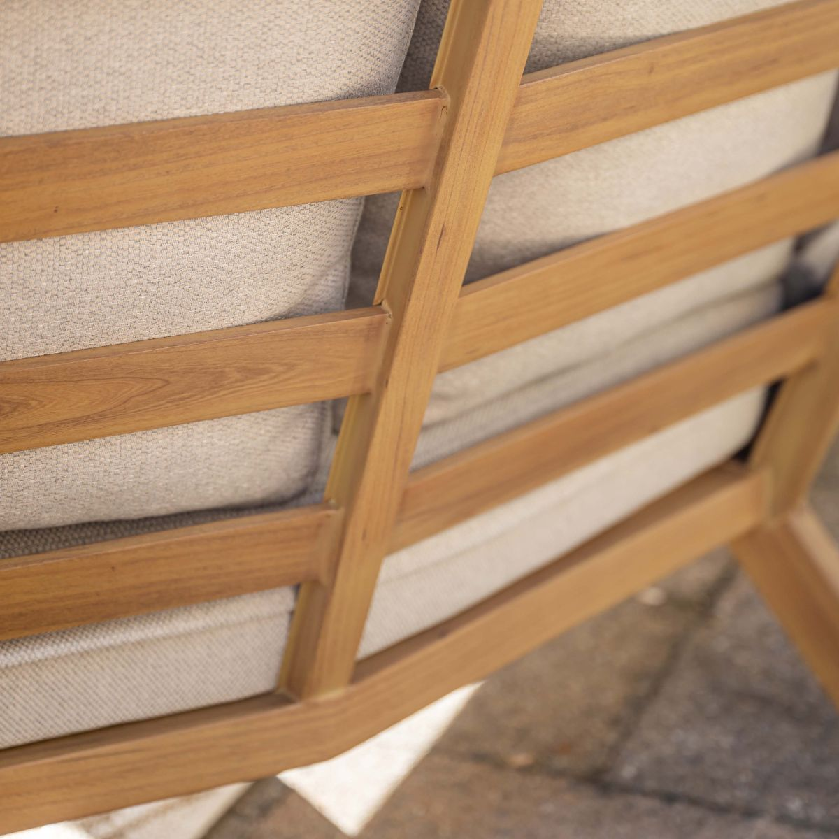 Wooden slatted sofa structure with light beige cushions, close-up view.
