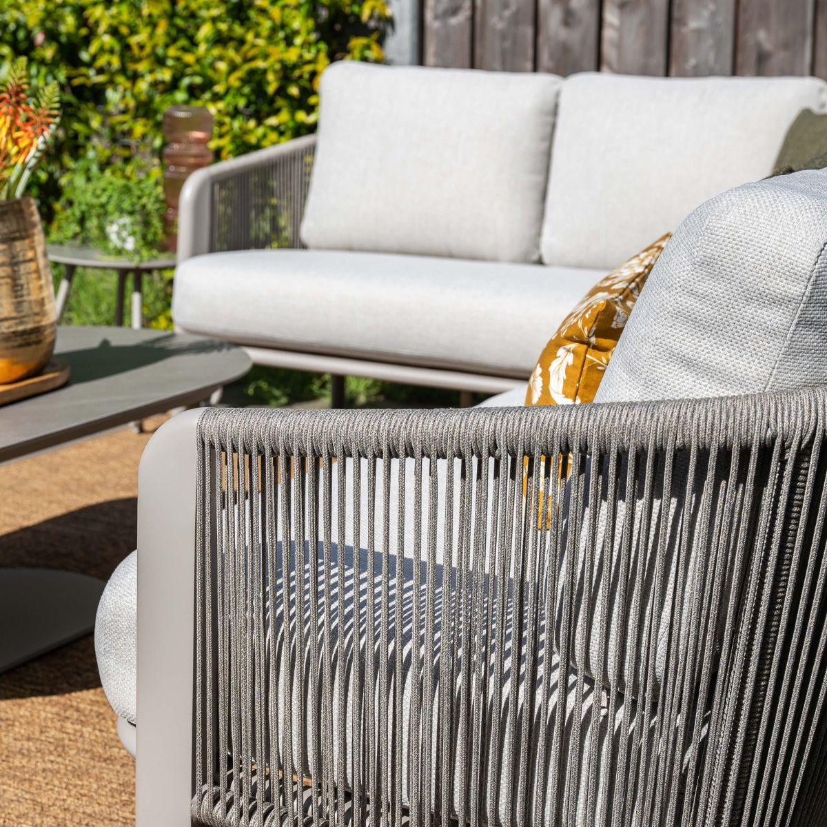 Outdoor patio furniture with white cushions, table and plants.