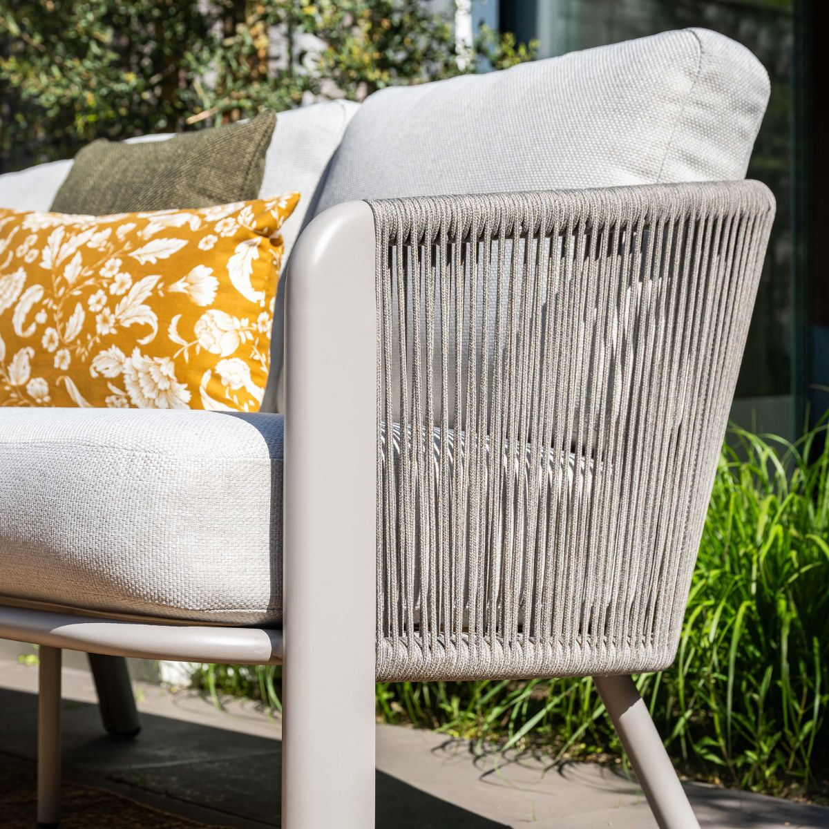 Gray outdoor sofa with yellow and green cushions, featuring a rope back.