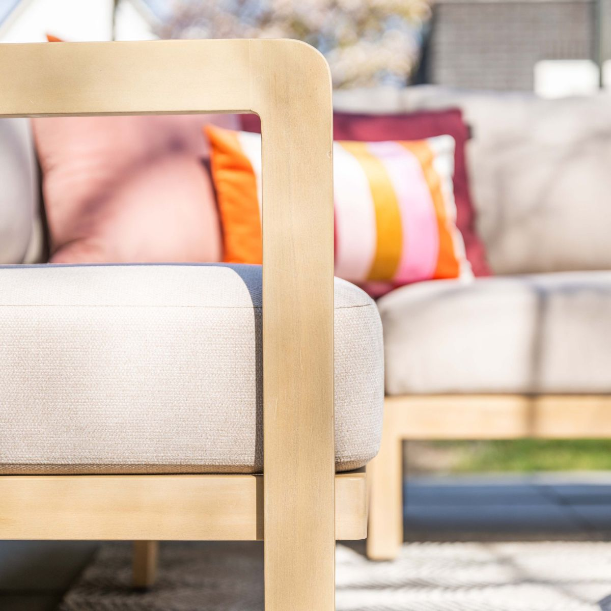 Een beige bank met kleurrijke kussens op een patio.