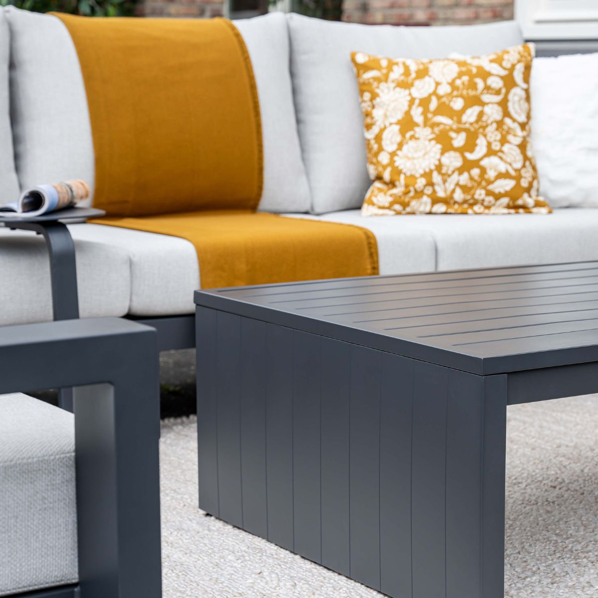 Gray coffee table and sofa with mustard yellow throw and pillows.