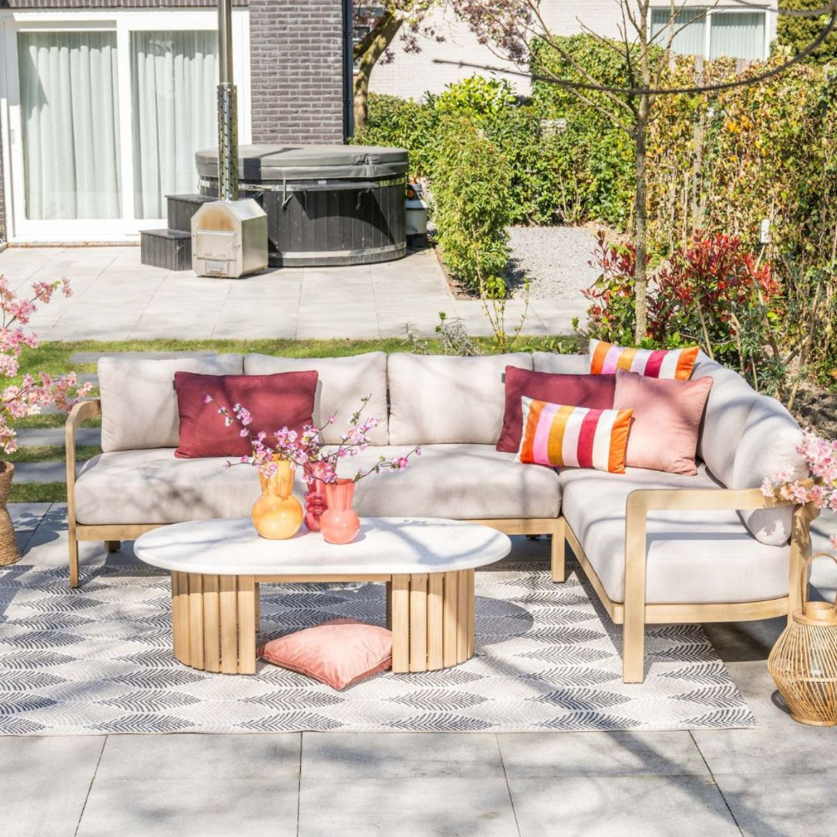Een hoekbank met kussens op een terras met een ovale salontafel.