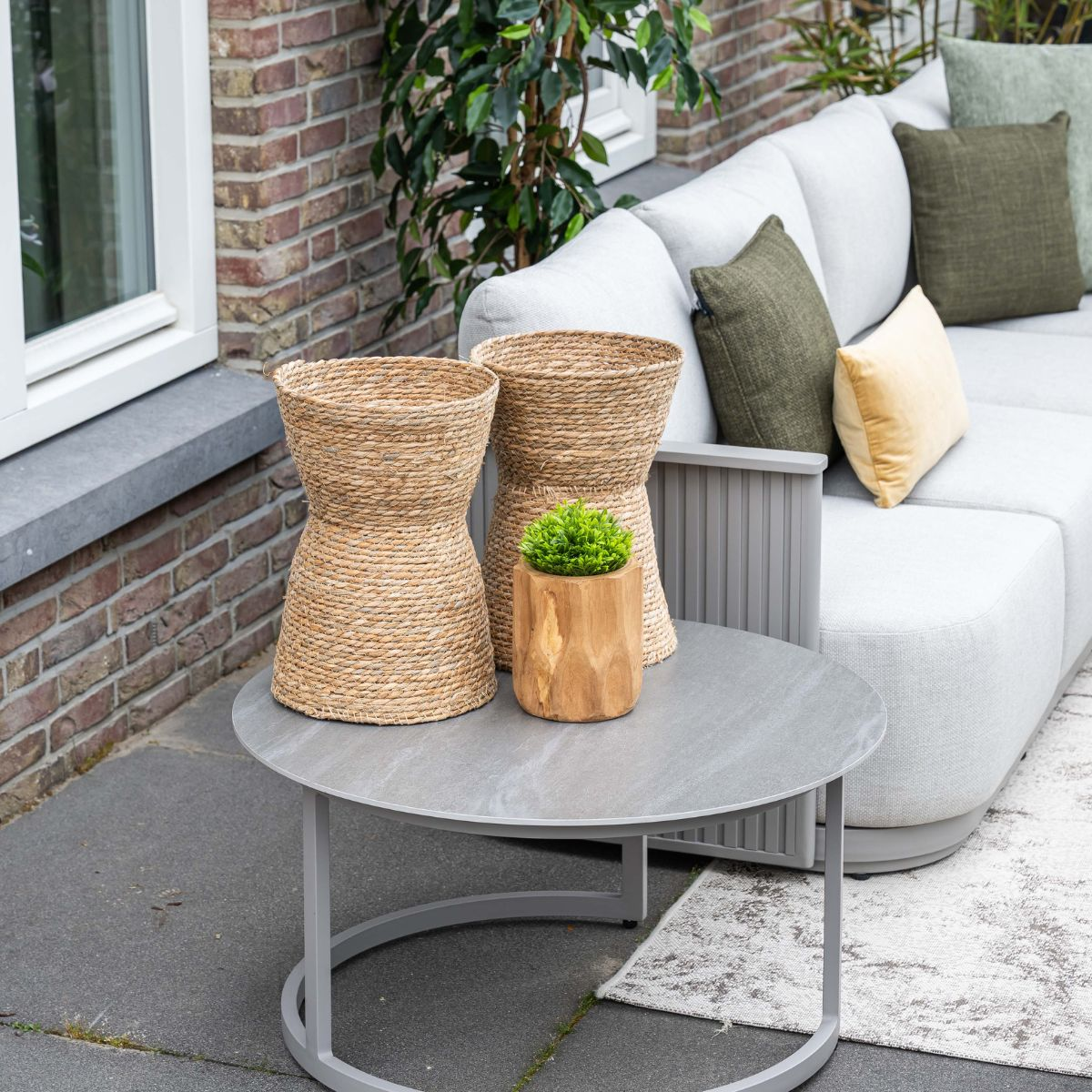 Twee gevlochten manden en een potplant op tafel voor een bank.