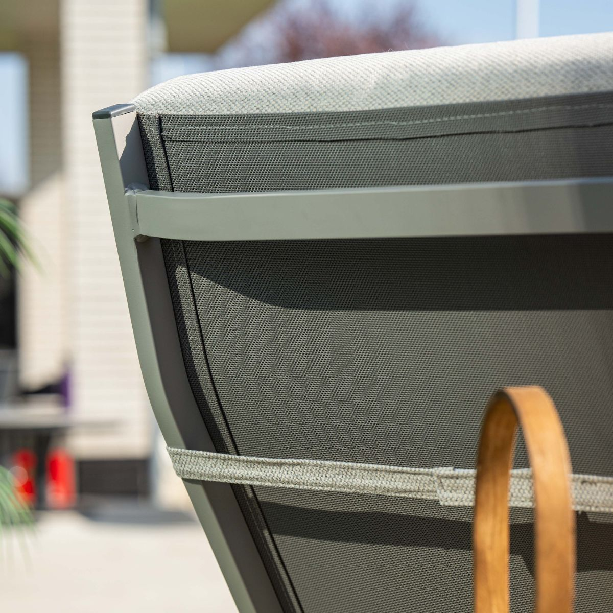 Grijze stoffen stoel met metalen frame en houten handvat buiten.