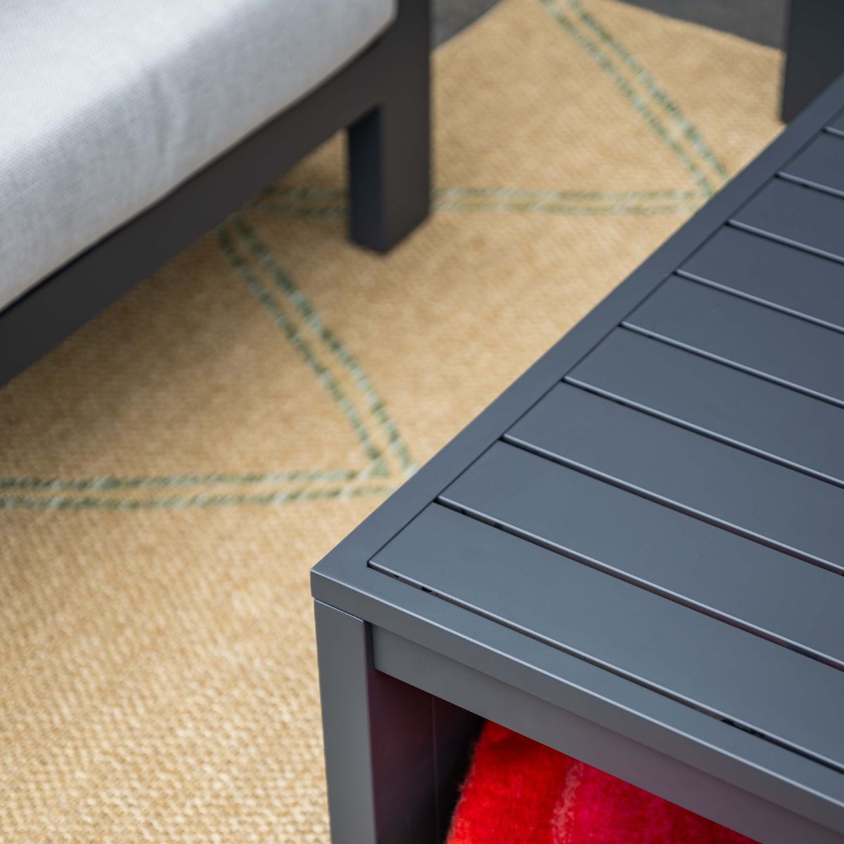 Dark gray table and couch leg on beige rug with green pattern.