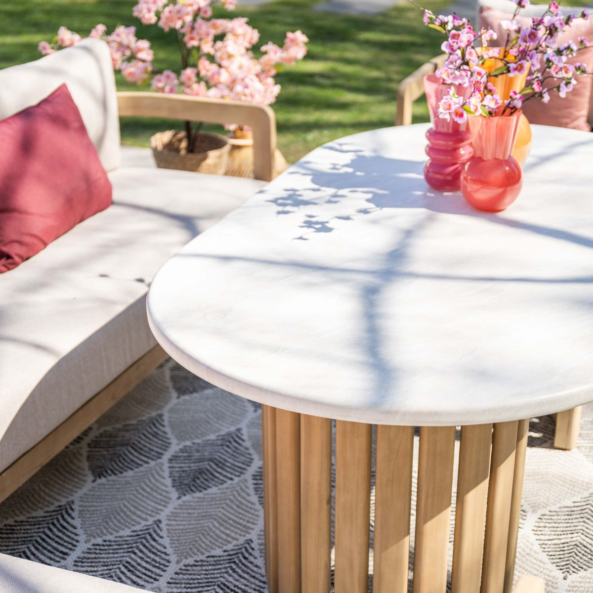 Een witte tafel met houten voet, ernaast een bank met een rood kussen.
