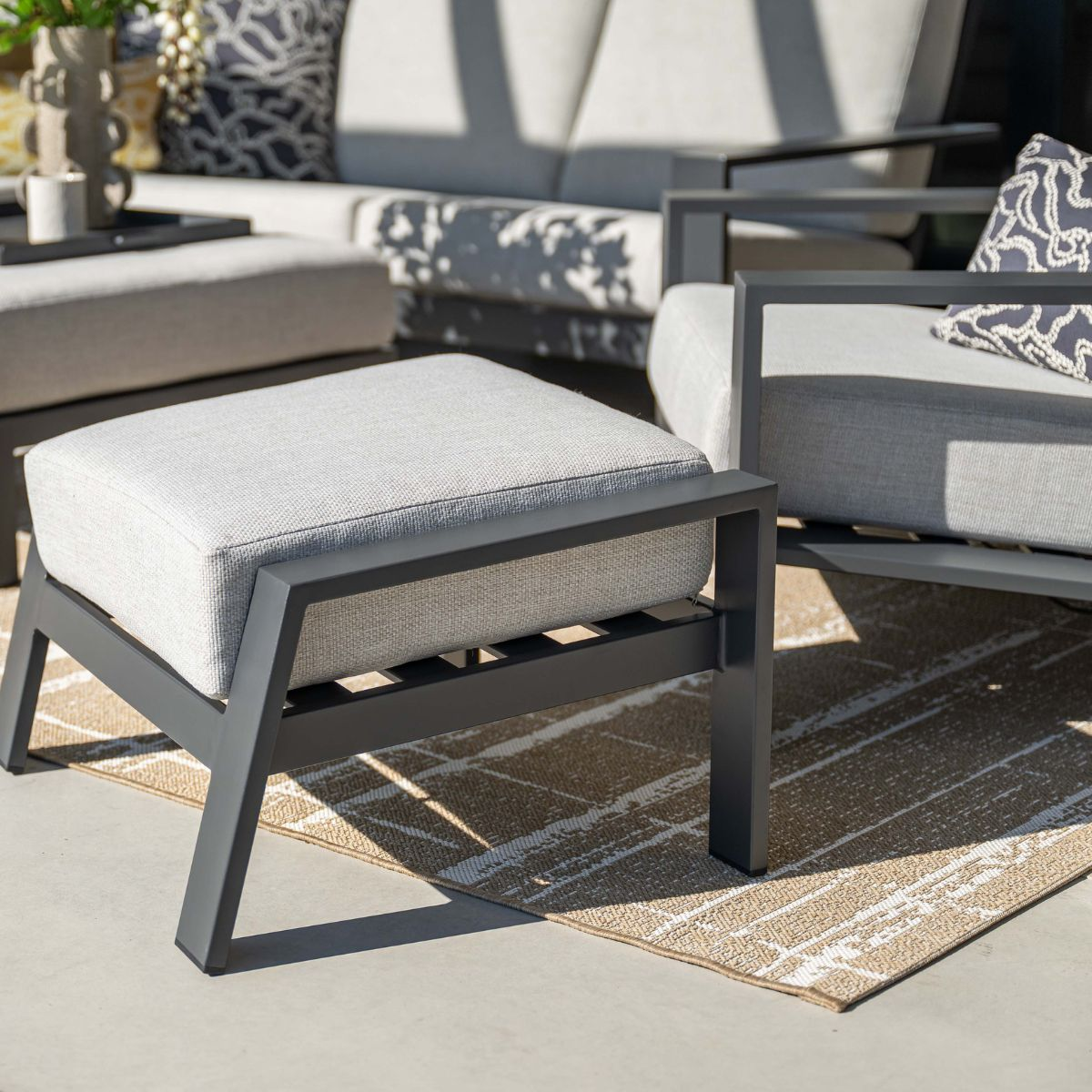 Gray outdoor furniture set with sun shadows on a patio.