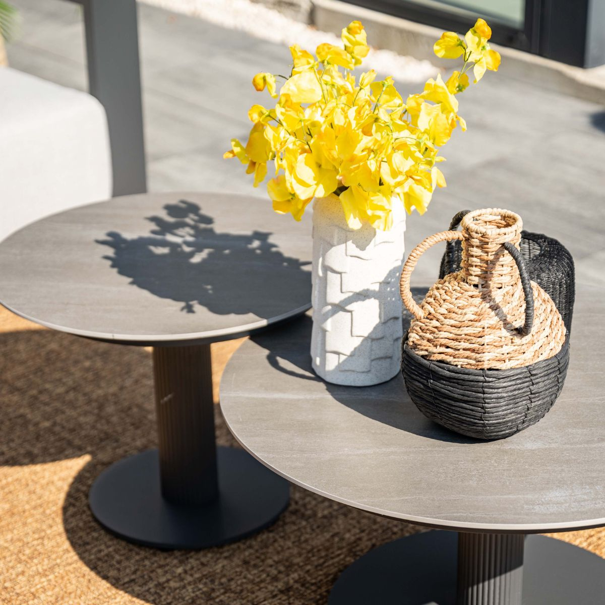 Two round tables with flowers and basket decor on a rug.