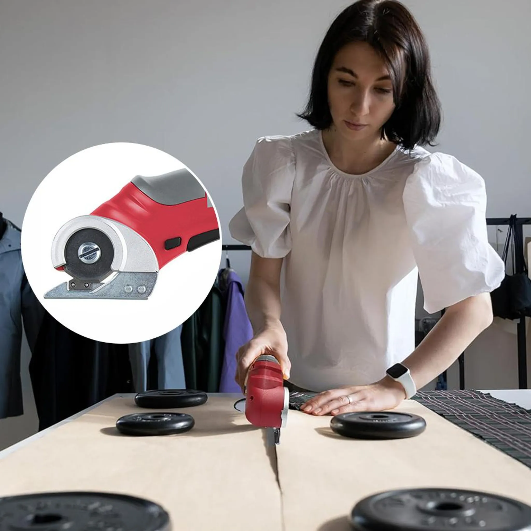 Eine Frau schneidet mit einem roten Rollschneider Stoff auf einem Tisch zu.