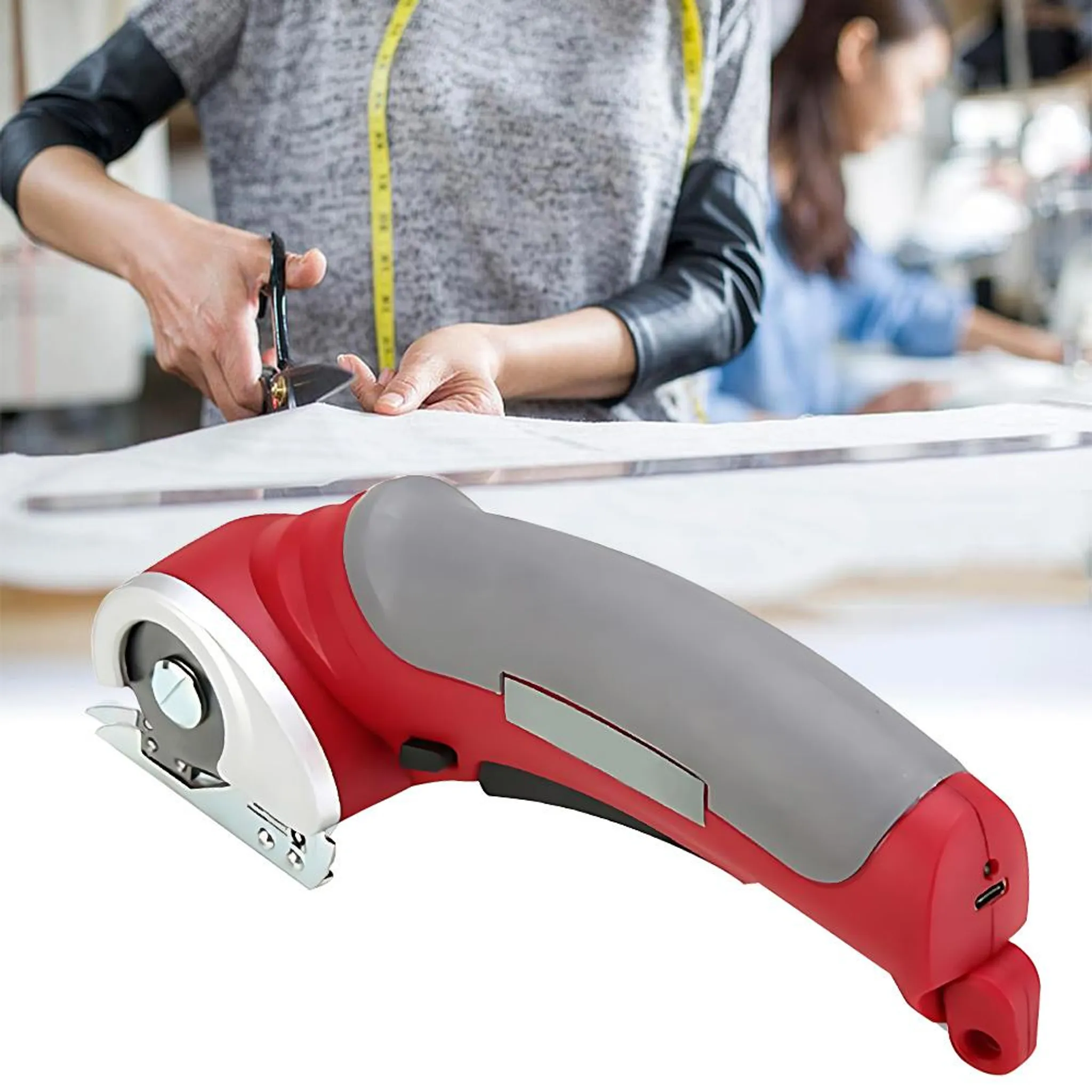 Rote und graue elektrische Stoffschere mit einem Mann, der Stoff schneidet.