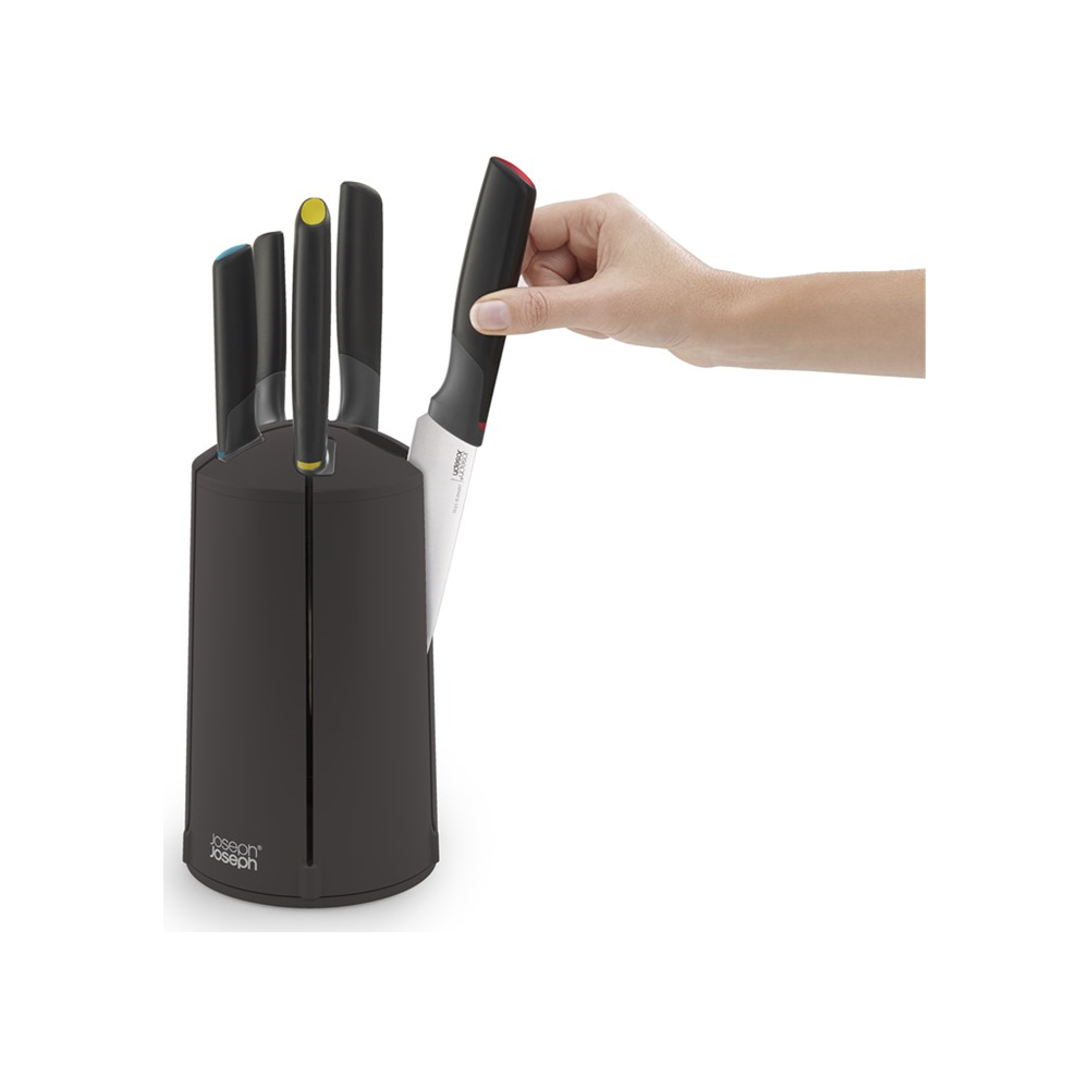 Une main retire un couteau d'un bloc à couteaux noir avec des manches colorés.