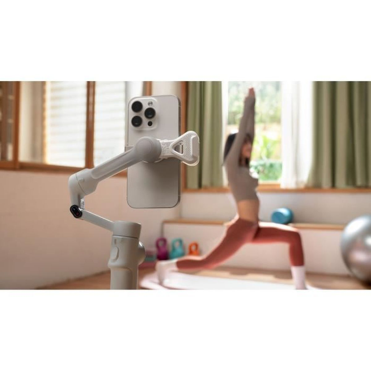 Uchwyt na telefon z telefonem po lewej. Kobieta ćwiczy jogę w tle.