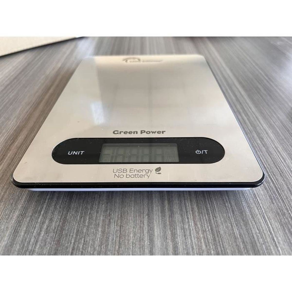 Eine silberne Digitalwaage mit schwarzem Display auf Holztisch.