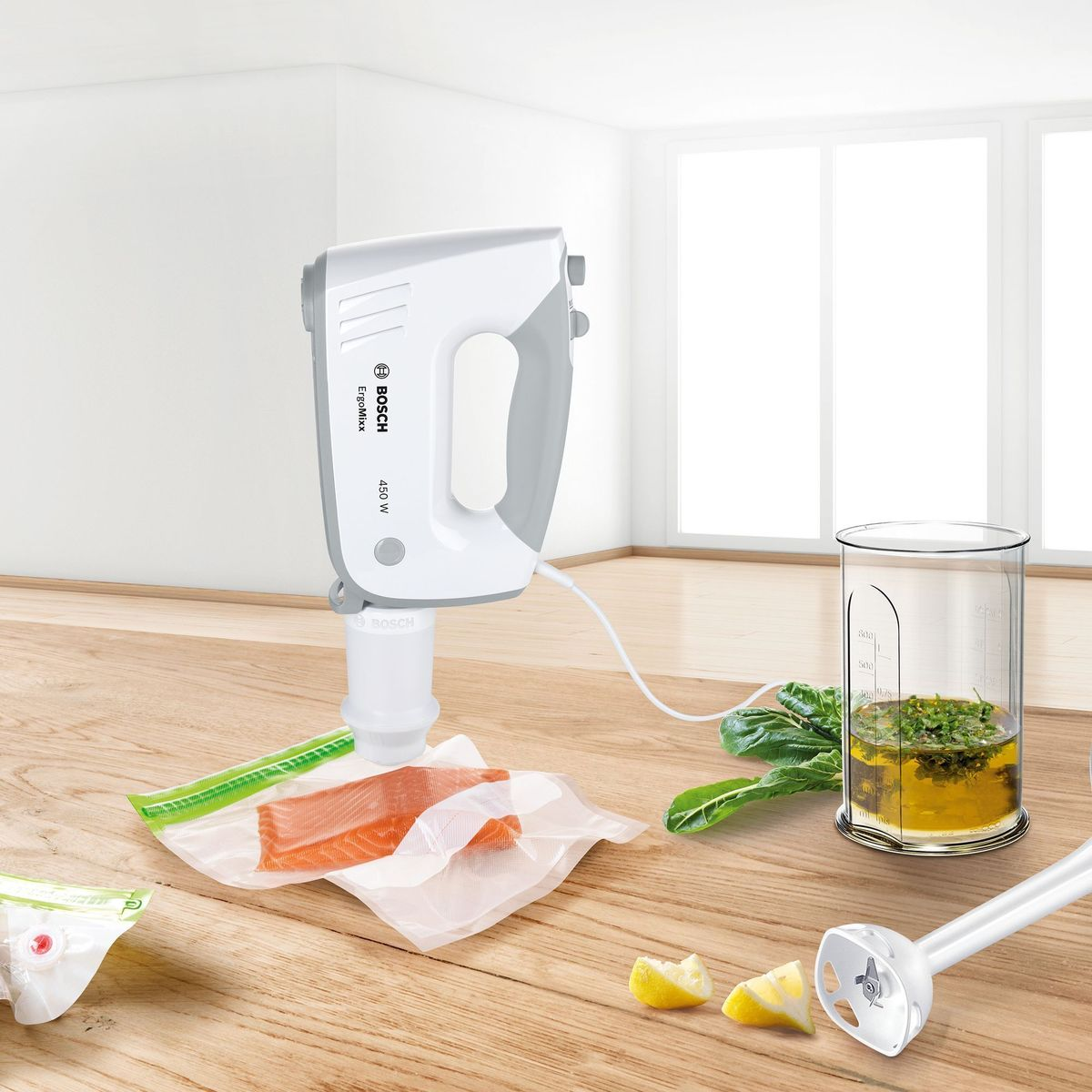 White and gray hand mixer over salmon in vacuum bag, with blender attachment and ingredients.