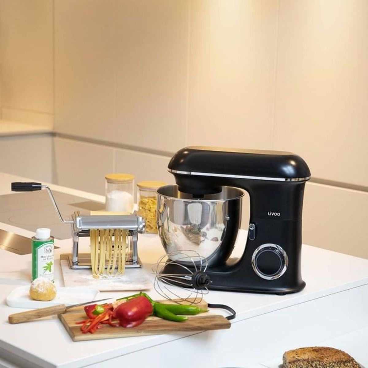 Robot kuchenny z maszynką do makaronu, warzywami i chlebem na blacie.