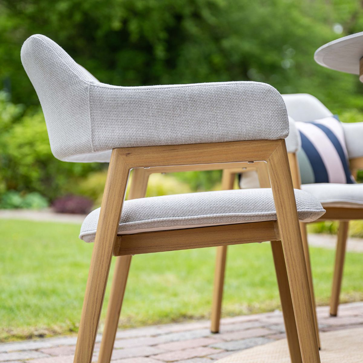 Gestoffeerde stoel met houten frame staat buiten op een stenen terras.