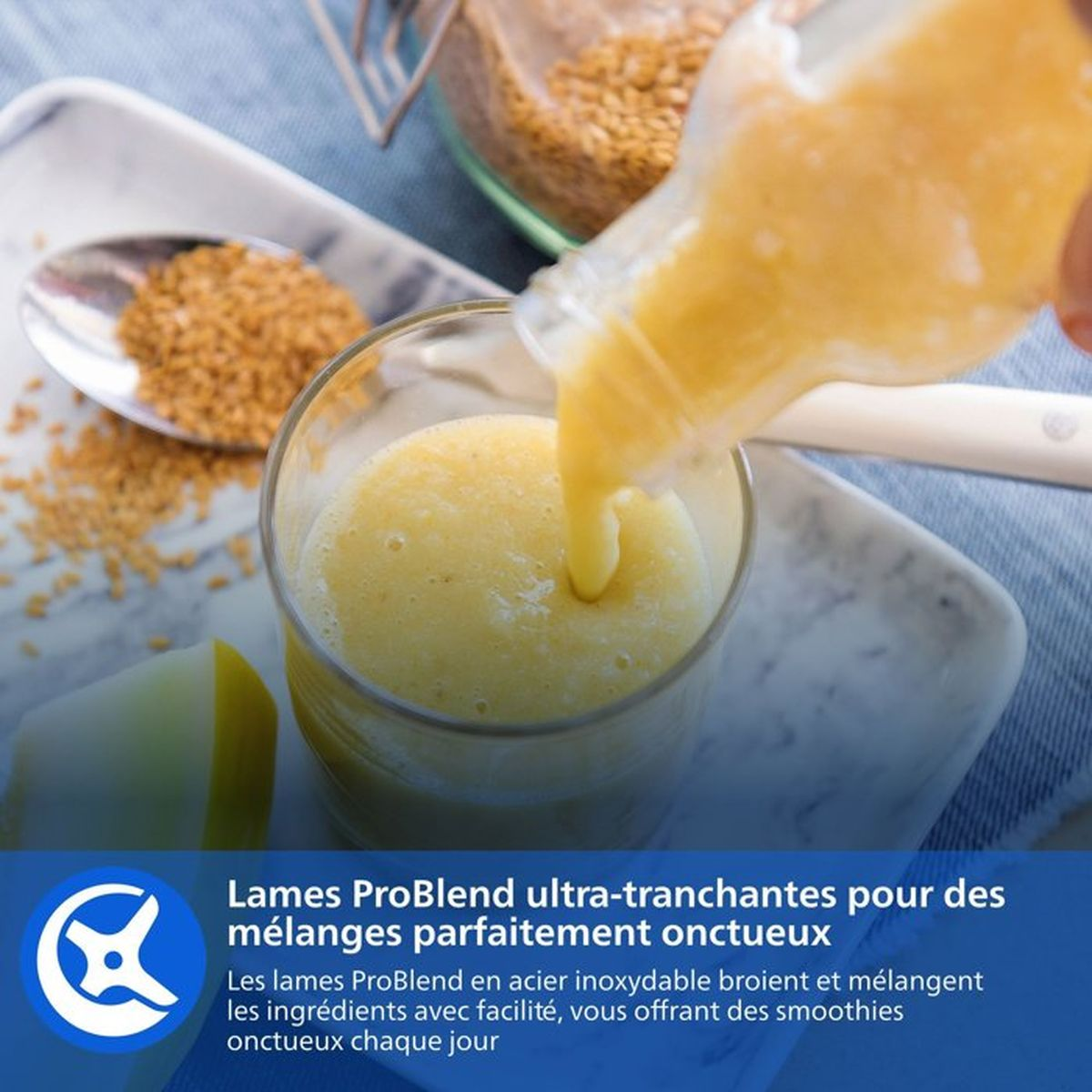 Gelber Smoothie wird in Glas gegossen, daneben Löffel mit Samen.