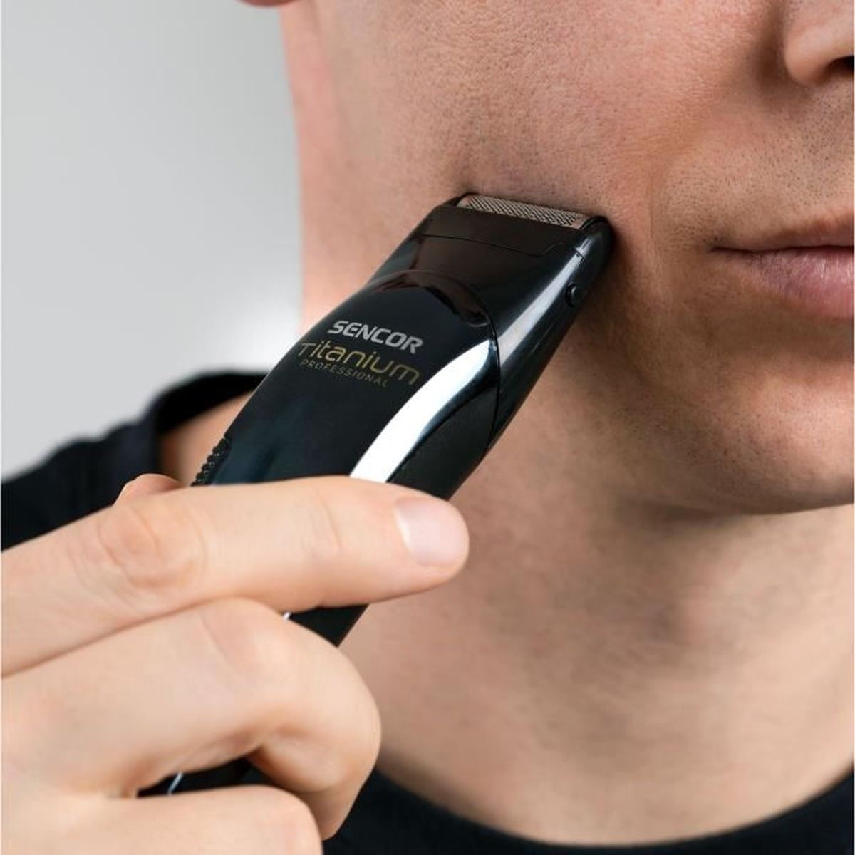 Ein Mann rasiert sich mit einem schwarzen SENCOR Trimmer im Gesicht.