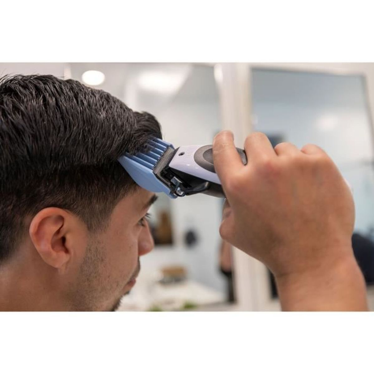 Mężczyzna strzyże włosy maszynką elektryczną.