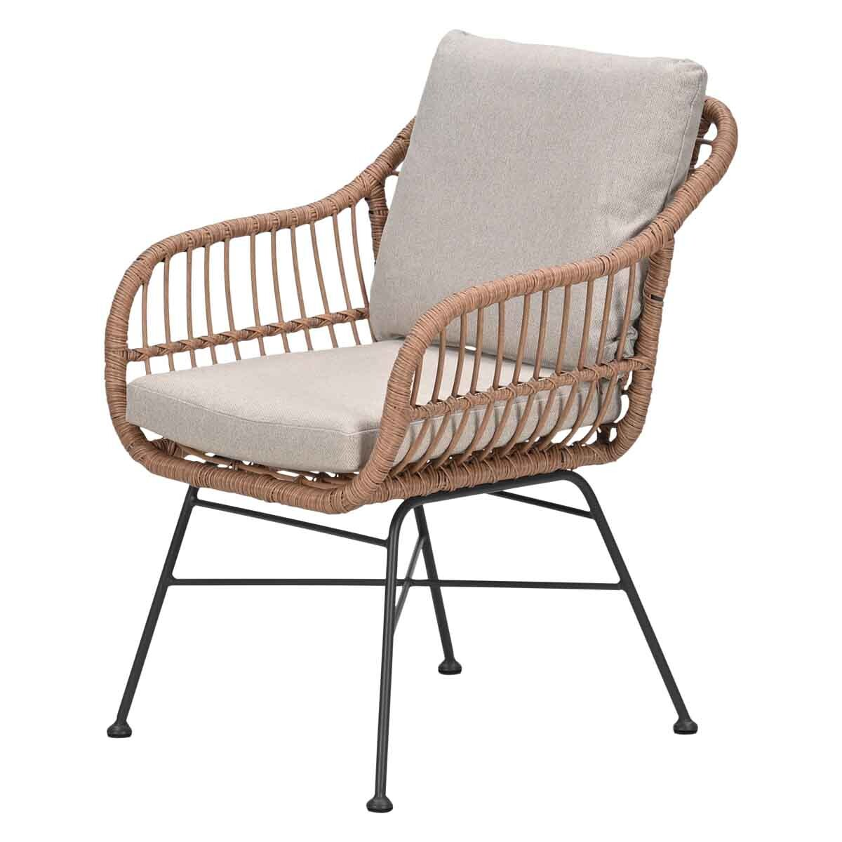 Een rieten fauteuil met lichte kussens en zwarte metalen poten.