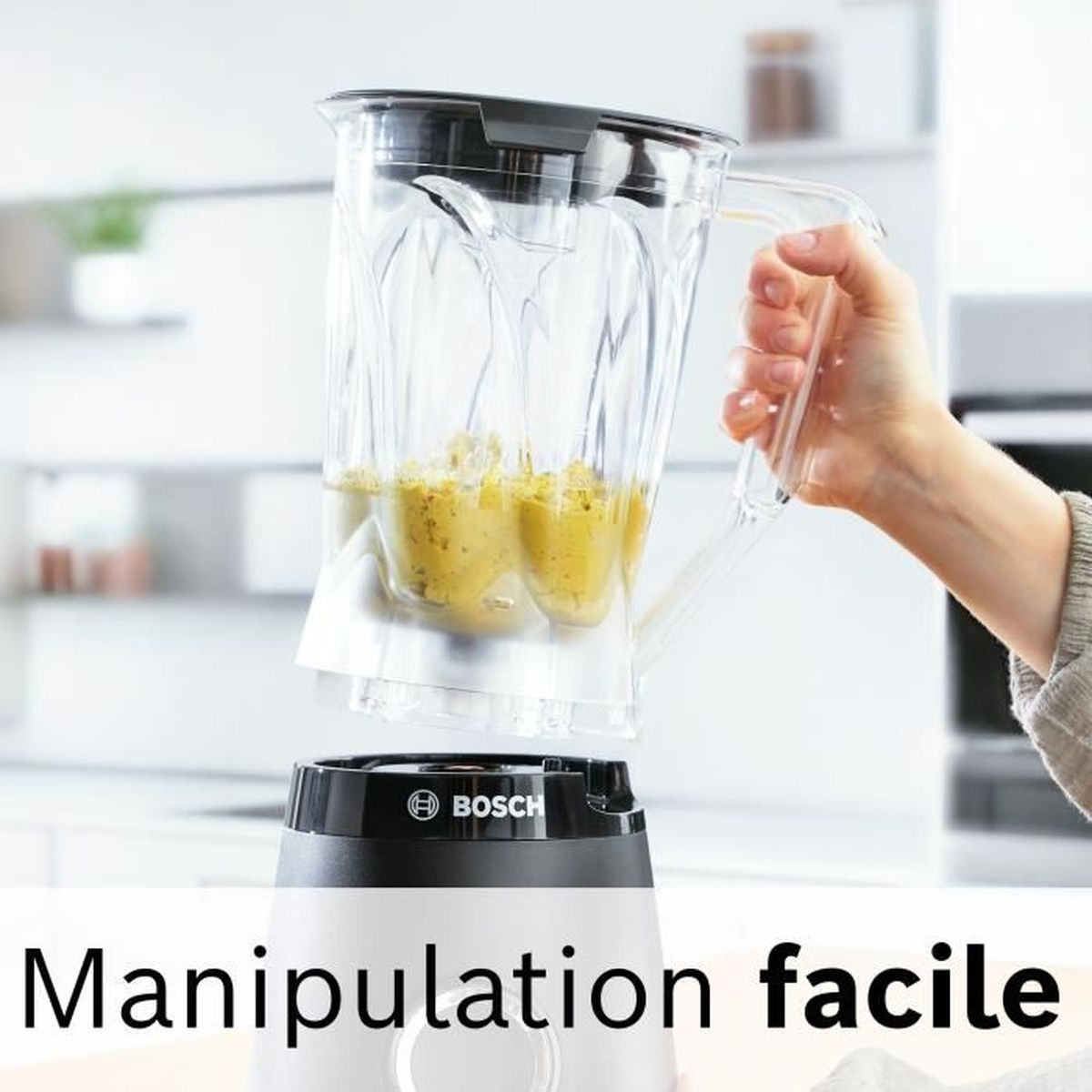 Una mano tiene il boccale di un frullatore Bosch con contenuto giallo.