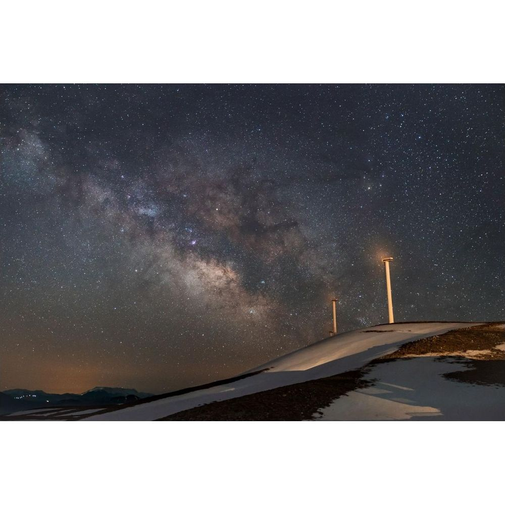Via Lattea su paesaggio innevato con due lampioni di notte.