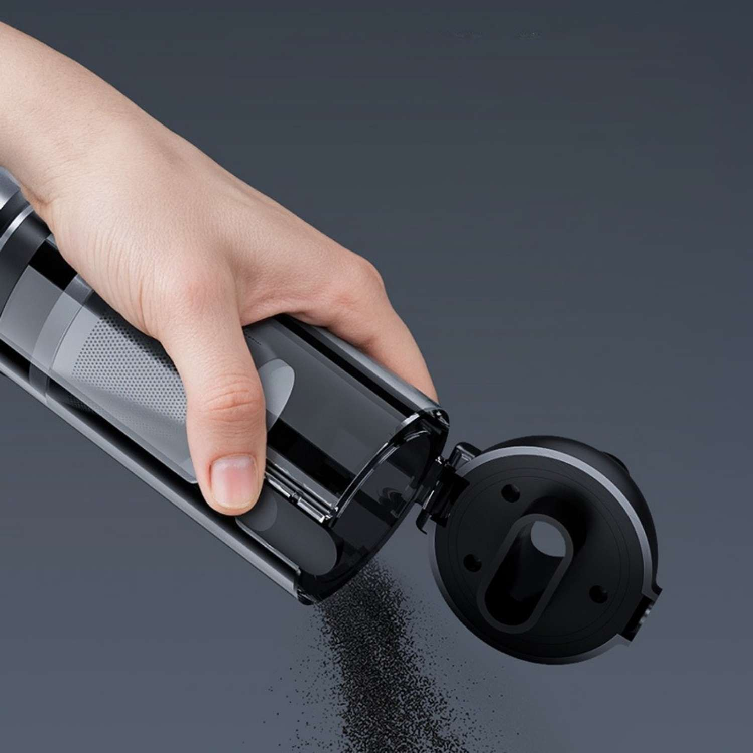 Hand kippt schwarzen Behälter aus, schwarzer Staub fällt heraus.