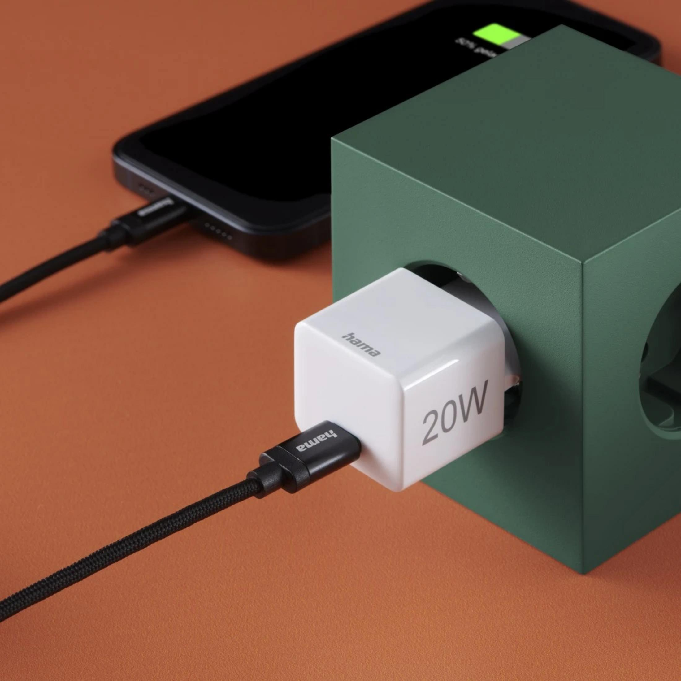 Un caricabatterie Hama bianco da 20W alimenta uno smartphone. Un cubo verde è accanto.