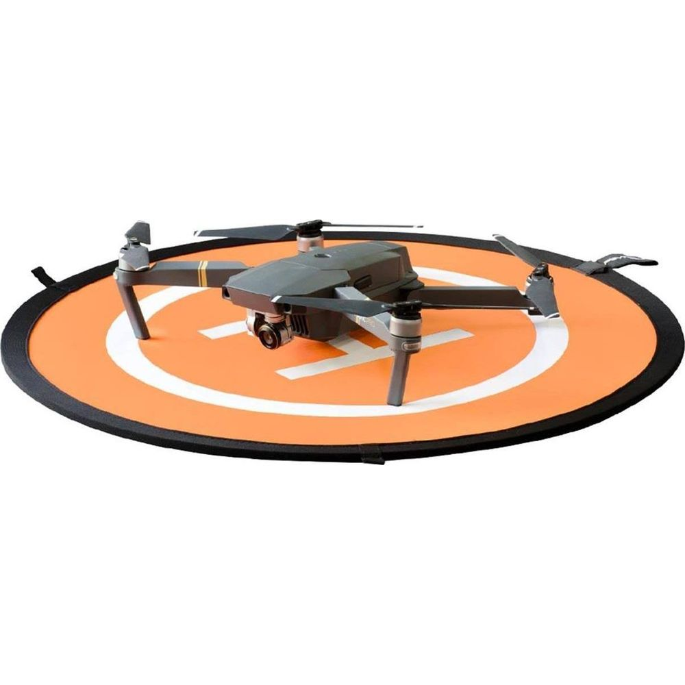 Un dron está sobre una plataforma de aterrizaje naranja con marcas blancas.