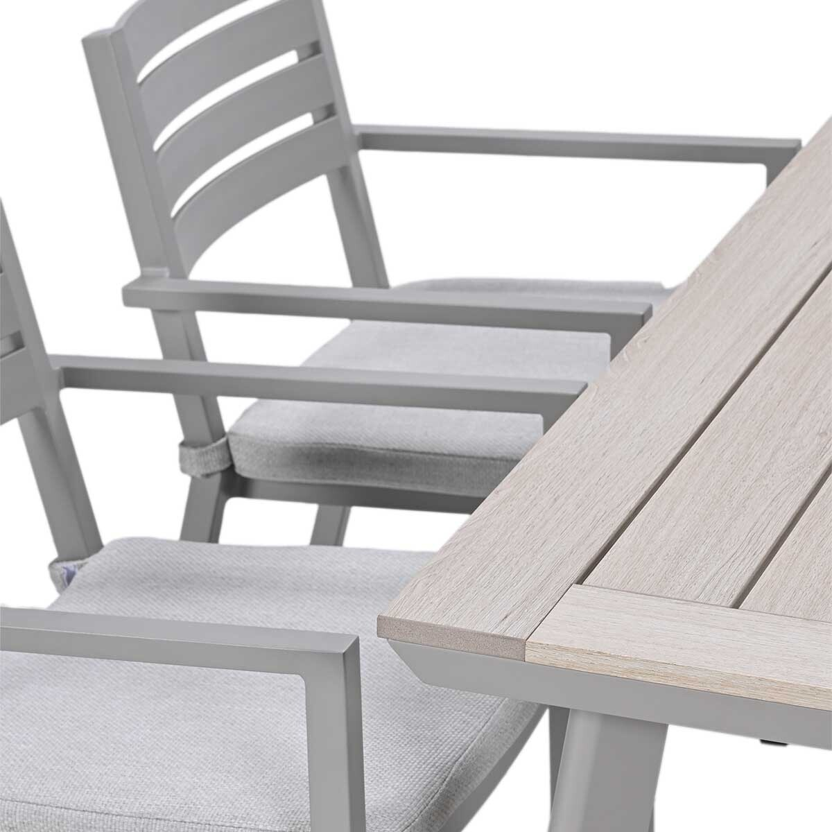 Grijze tuinstoelen met gestoffeerde zittingen naast een tafel met houtlook blad.
